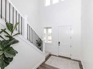 Foyer featuring healthy amount of natural light, a towering ceiling, stairway, and wood finished floors