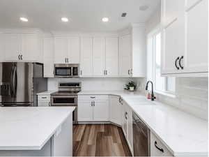 Kitchen featuring stainless steel appliances, plenty of natural light, white cabinets, light wood-style flooring, and recessed lighting