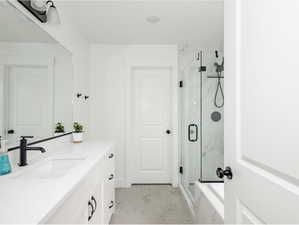 Full bathroom with vanity, a marble finish shower, and marble look tiles