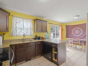 Kitchen featuring dishwasher, a peninsula, range with electric cooktop, light stone countertops, and dark brown cabinets