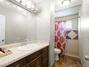 Bathroom with vanity, tiled shower, and stone finish floors