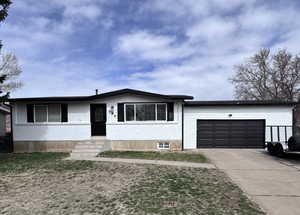 View of front facade with an attached garage, brick siding, concrete driveway, and a front yard