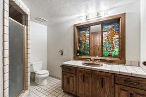 Bathroom featuring vanity, a stall shower, tile patterned flooring, and a textured ceiling