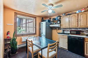 Kitchen featuring black appliances, light brown cabinets, a baseboard heating unit, light countertops, and a textured ceiling