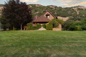 View of front facade with a front yard, a mountain view, and a chimney