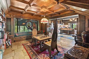 Dining area featuring a wooden ceiling with exposed beams, stone tile flooring, wooden walls, coffered ceiling, and ornamental molding