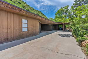 View of side of property with driveway, an attached garage, and a carport