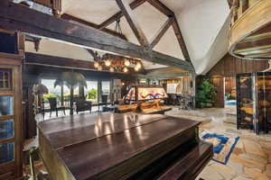 Community lobby with high vaulted ceiling, a textured ceiling, beam ceiling, and wood walls