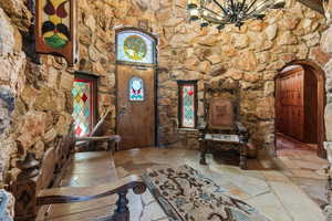 Entrance foyer featuring stone floors, arched walkways, and a chandelier