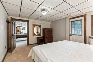 Bedroom featuring light carpet and a drop ceiling
