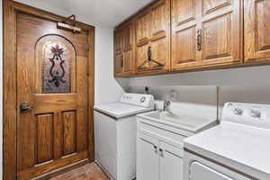 Laundry area with cabinet space, washing machine and dryer, and wood finished floors