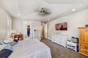 Bedroom featuring dark carpet, recessed lighting, a ceiling fan, and a tray ceiling