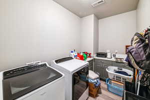 Laundry area featuring washer and clothes dryer, light wood-style flooring, and cabinet space