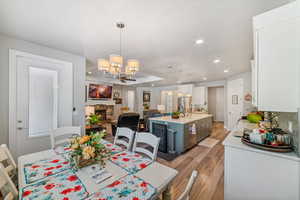 Dining space with a chandelier, light wood-style floors, a fireplace, and recessed lighting
