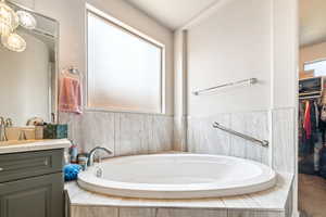 Bathroom featuring vanity, a bath, and a walk in closet