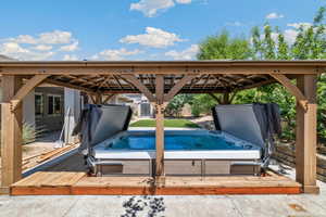 View of pool with a covered hot tub and a gazebo