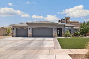 Prairie-style house with stone siding, a garage, driveway, a tile roof, and a front yard
