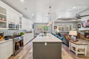 Kitchen with stainless steel appliances, open floor plan, ceiling fan, an island with sink, and recessed lighting