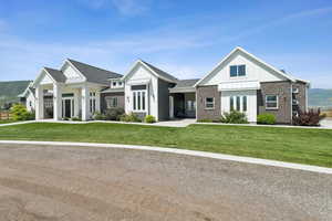 View of front facade featuring board and batten siding, a front lawn, a standing seam roof, and brick siding