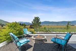 View of patio featuring a fire pit, a mountain view, and a rural view
