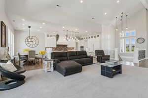 Living area with a towering ceiling, recessed lighting, light colored carpet, and a chandelier