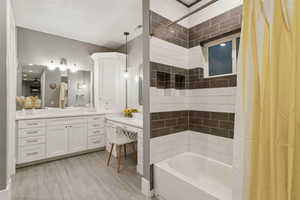Bathroom featuring vanity, shower / bath combo with shower curtain, and wood finished floors