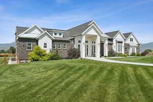 View of front of house featuring board and batten siding, a front yard, brick siding, and a mountain view
