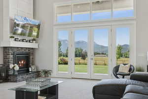 Carpeted living room with a mountain view, healthy amount of natural light, a fireplace, and a towering ceiling