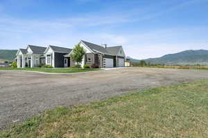View of front of house with an attached garage, driveway, a mountain view, and a front lawn