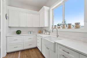 Kitchen with white cabinets, dark wood-type flooring, and light stone counters