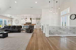 Living area featuring light wood-style floors, a towering ceiling, and recessed lighting
