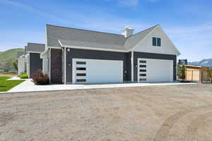 View of home's exterior featuring a garage, a mountain view, driveway, and roof with shingles