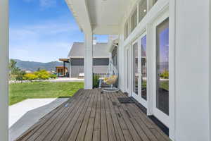 Wooden terrace featuring a mountain view, a lawn, and french doors