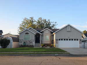 Ranch-style house featuring concrete driveway, stone siding, and stucco siding