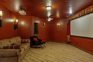 Cinema room with a textured ceiling, light wood-style flooring, and a ceiling fan