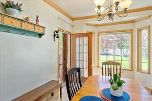 Dining area featuring crown molding, a chandelier, and wood finished floors. Additional exterior door allows access to the front covered porch.