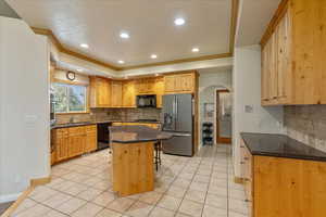 Kitchen featuring black appliances, arched walkways, tasteful backsplash, a breakfast bar area, and recessed lighting