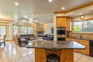 Kitchen with a center island, vaulted ceiling, stainless steel double oven, dark stone counters, and a textured ceiling
