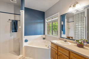 Primary Bathroom with a whirlpool tub, walk in shower, and vanity