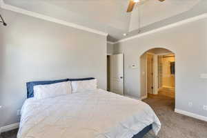 Primary Bedroom featuring ornamental molding, arched walkways, ceiling fan, and a raised ceiling