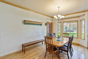 Dining room featuring light wood-type flooring, ornamental molding, and a chandelier
