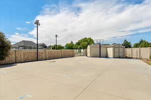 View of sports court featuring two storage sheds.
