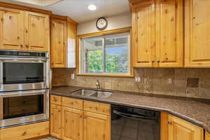 Kitchen with dishwasher, double oven, decorative backsplash, and a textured ceiling