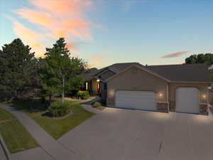 Rambler featuring a garage, driveway, stucco siding, a front yard, and stone siding