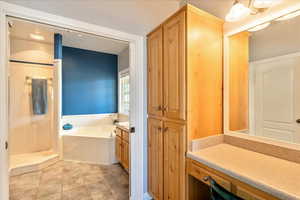 Primary Bathroom featuring vanity, a garden tub, and tile patterned flooring
