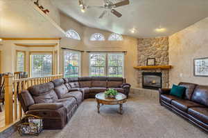 Carpeted living room with healthy amount of natural light, a textured ceiling, a fireplace, and ceiling fan