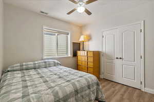 Bedroom 3 with light wood-style flooring, a textured ceiling, a closet, and a ceiling fan