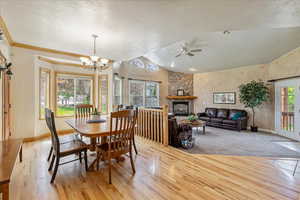 Dining room with a textured ceiling, light wood-style floors, lofted ceiling, and a chandelier