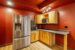 Home Theater kitchenette with fridge, light wood finished floors, and a raised ceiling