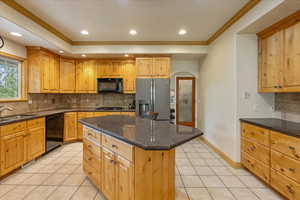 Kitchen featuring black appliances, arched walkways, light tile patterned floors, ornamental molding, and backsplash